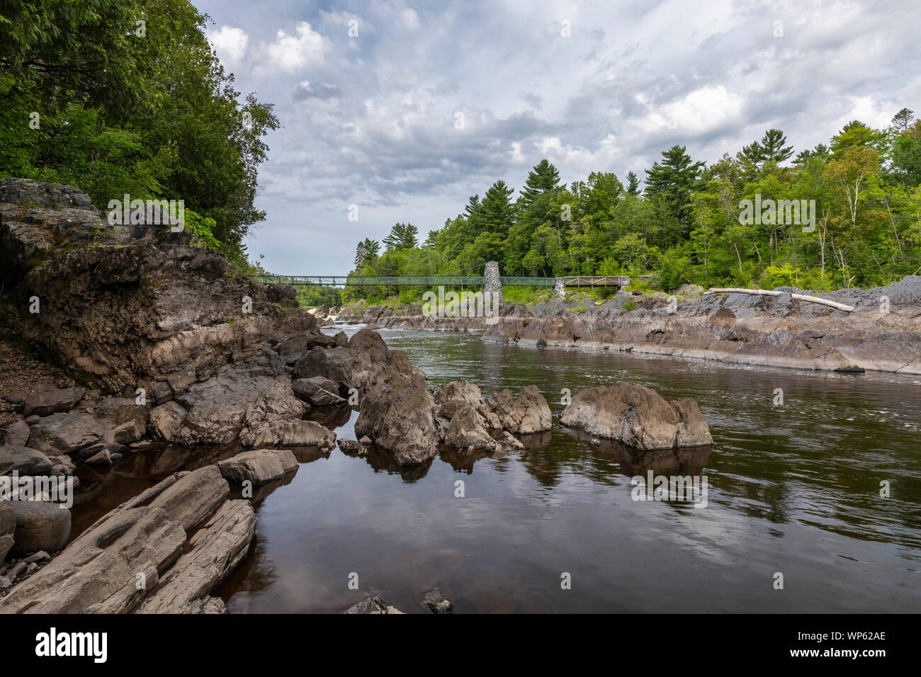 A rocky river landscape with a footbridge Stock Photo - Alamy