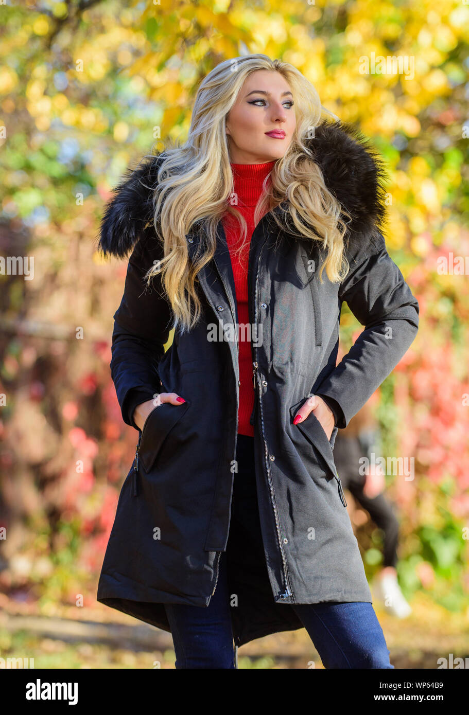 Modern outfit for youth. Girl in warm coat stand in park nature background  defocused. Woman long blonde hair wear stylish outfit with parka. Create  fall outfit to feel comfortable and pretty Stock