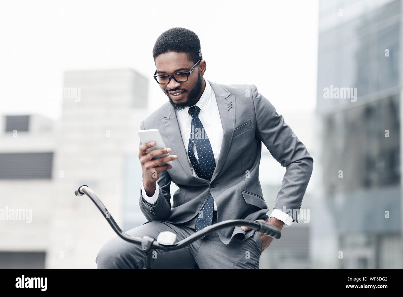 Handsome businessman using smartphone, riding on bicycle Stock Photo