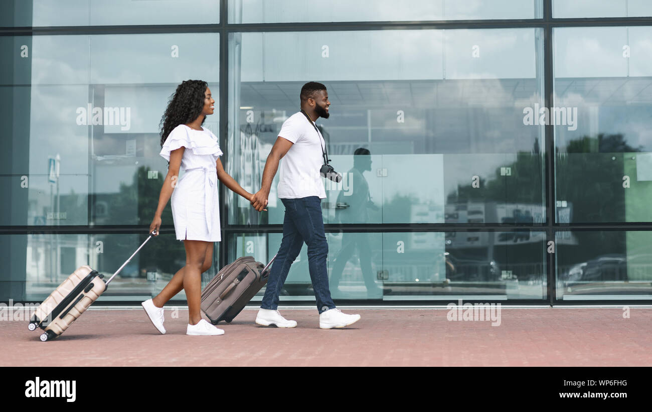 Happy african couple walking with luggage near modern airport Stock ...
