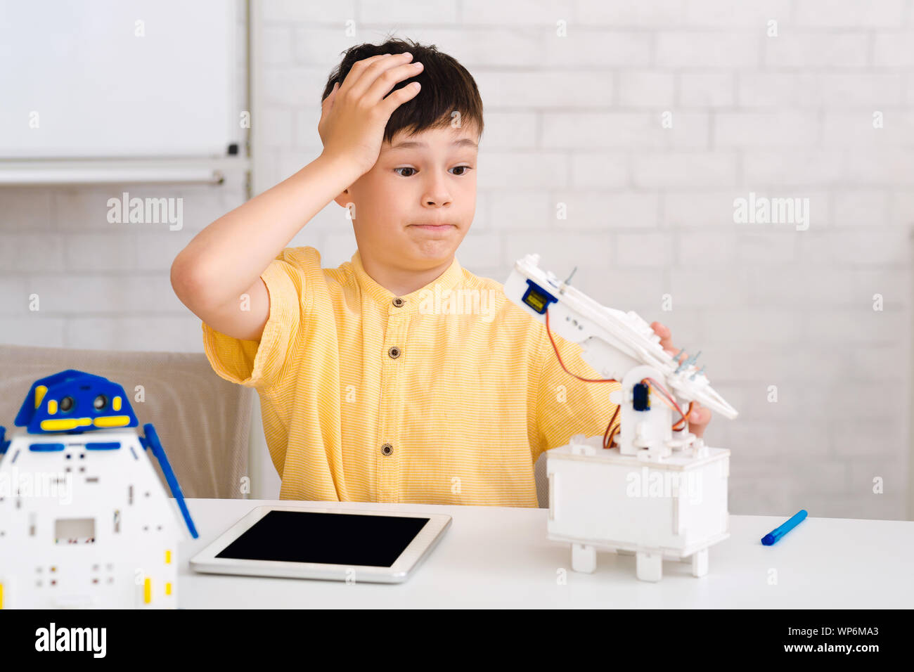 Stem education. Dismayed boy creating robot and made mistake Stock Photo