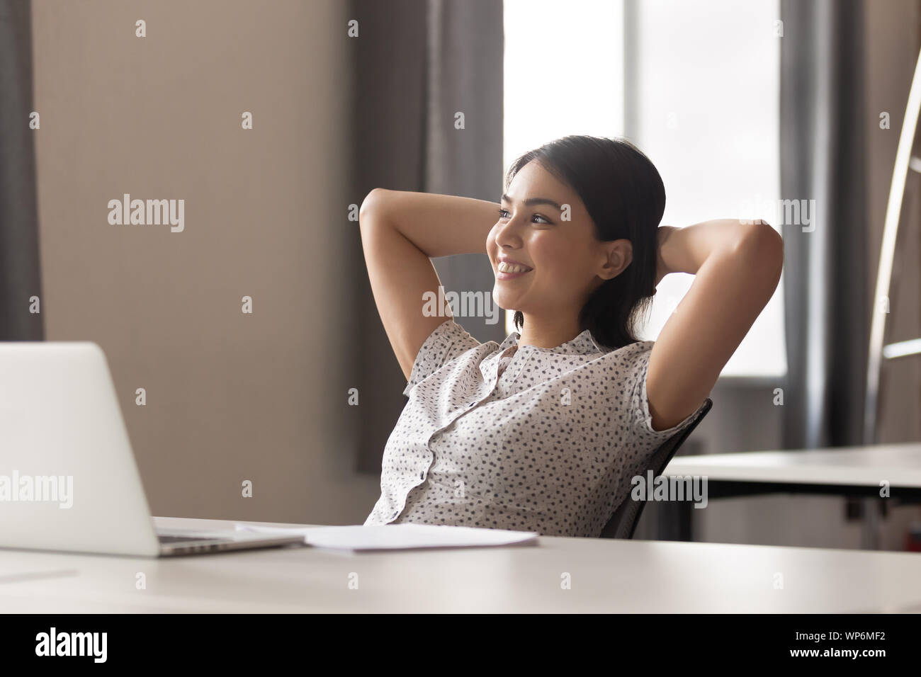 Happy peaceful asian female employee relaxing during working day break. Stock Photo