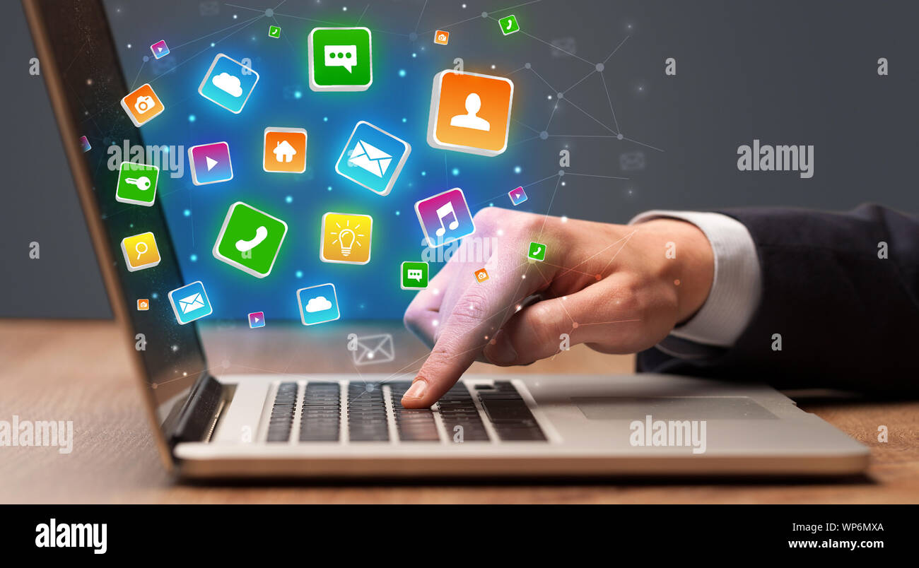 Businessman hand typing on laptop with flying application icons around ...