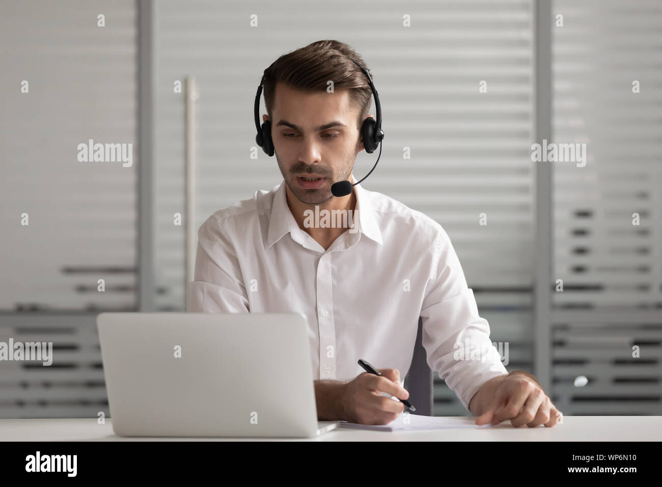Busy concentrated manager wearing headphones discussing project ideas with client. Stock Photo