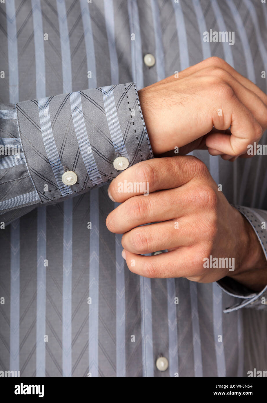 Close up detail of man's hands buttoning shirt cuffs. Men's clothing styles. Stock Photo