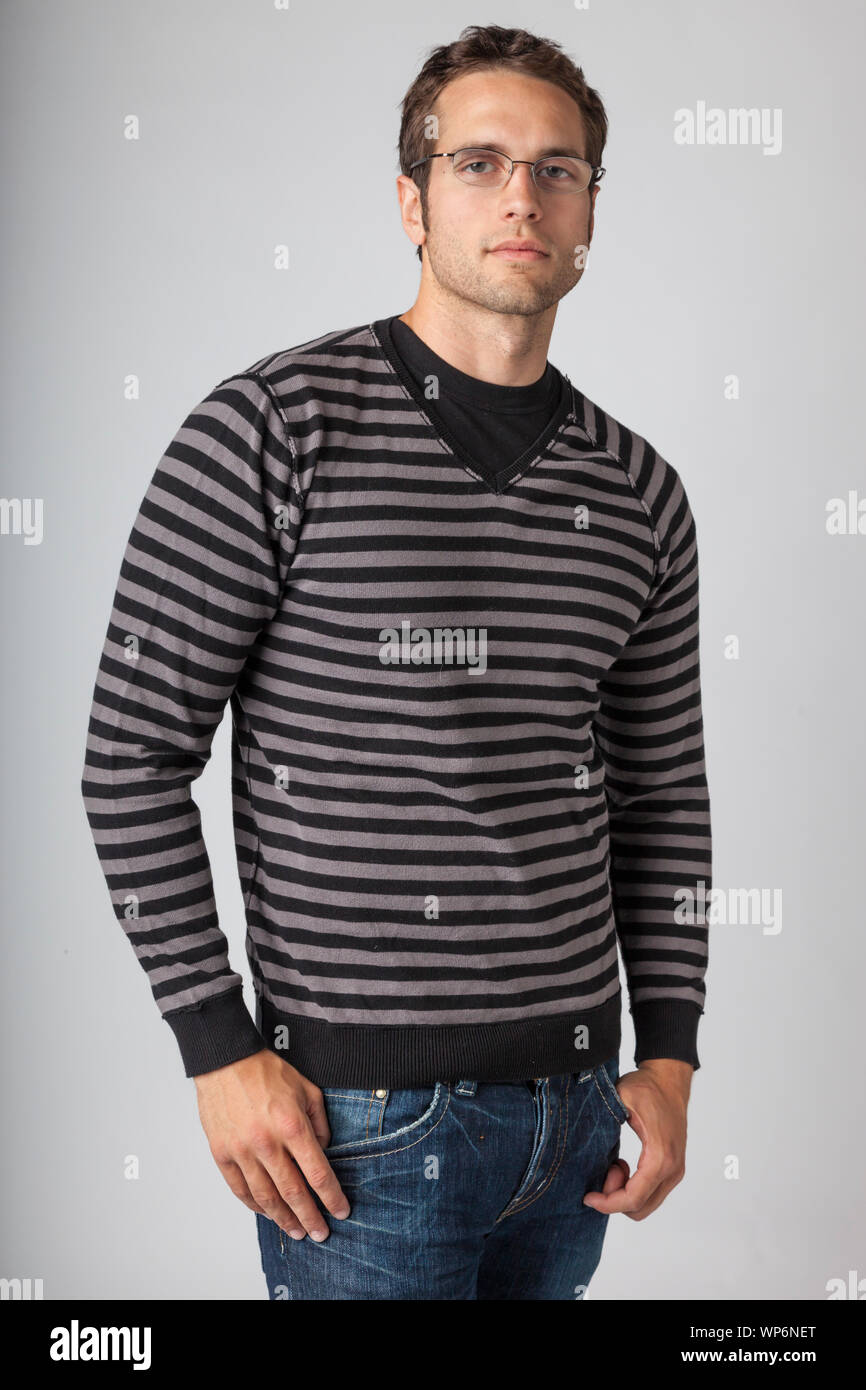 Man wearing striped sweater, jeans and eyeglasses. Young men's casual clothing apparel styles. Stock Photo