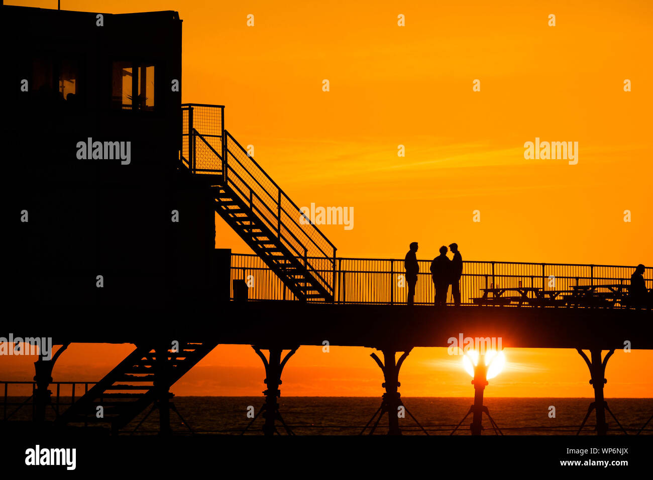 Aberystwyth Wales UK, Saturday 07 September 2019  UK Weather: People are silhouetted by the  beautiful early autumn sunset over Aberystwyth Pier, Wales UK, at the end of a day of clear skies and warm sunshine, tempered by a cold northerly breeze. Photo credit Keith Morris / Alamy Live News Stock Photo