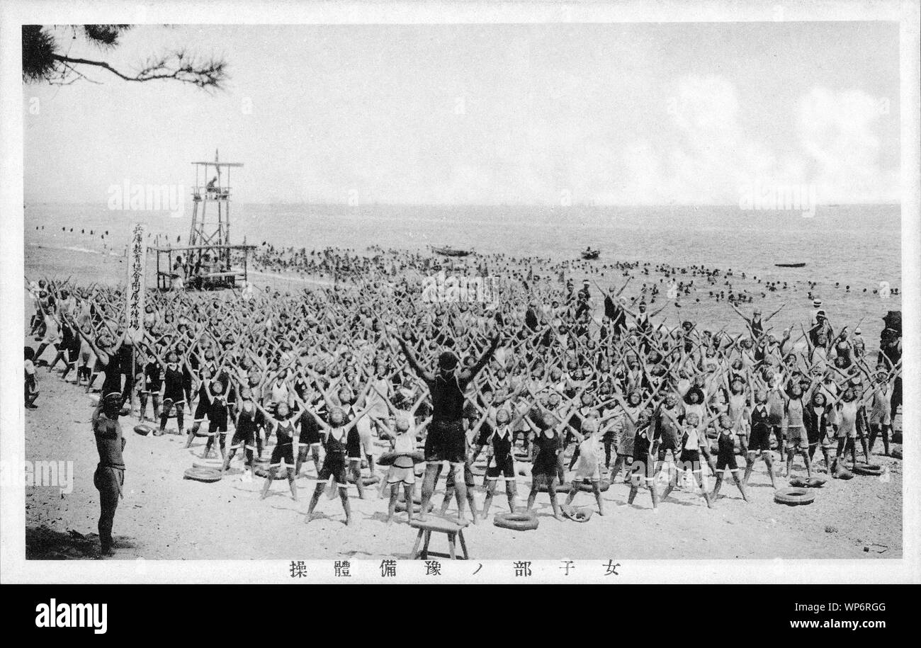 [ 1920s Japan - Gymnastic Exercises by Young Girls ] —   Young female students do gymnastic exercises on Suma Beach in Kobe, Hyogo Japan in July 1927 (Showa 2).  Mass exercises like this were very popular during the early Showa Period (1926-1989).  20th century vintage postcard. Stock Photo