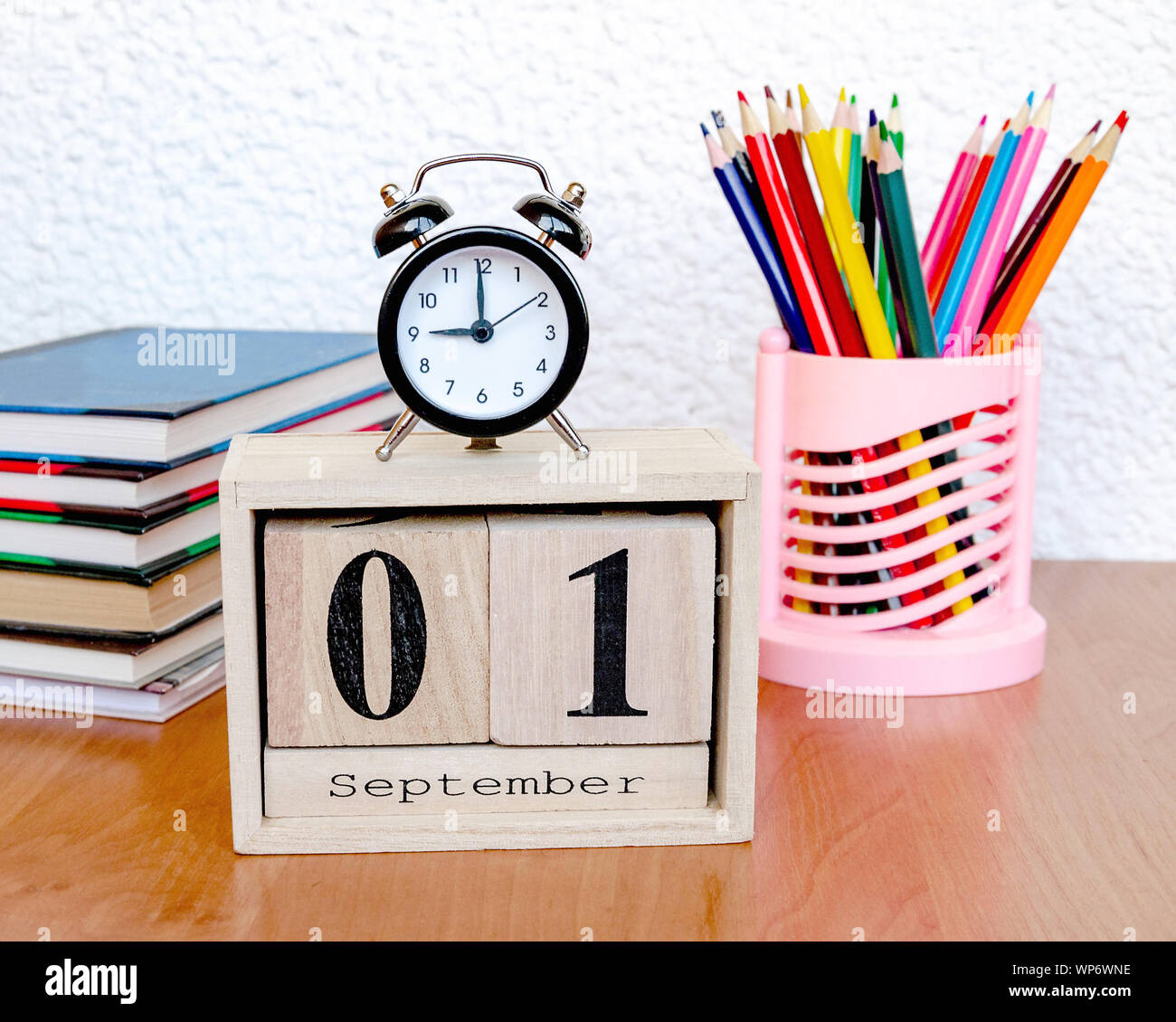 intermittent wooden calendar with the date of the first of September and an alarm clock, colored pencils on the table, a reminder of the school, close Stock Photo