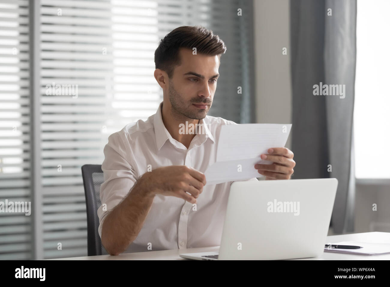 Concentrated young executive manager looking through financial documentation. Stock Photo