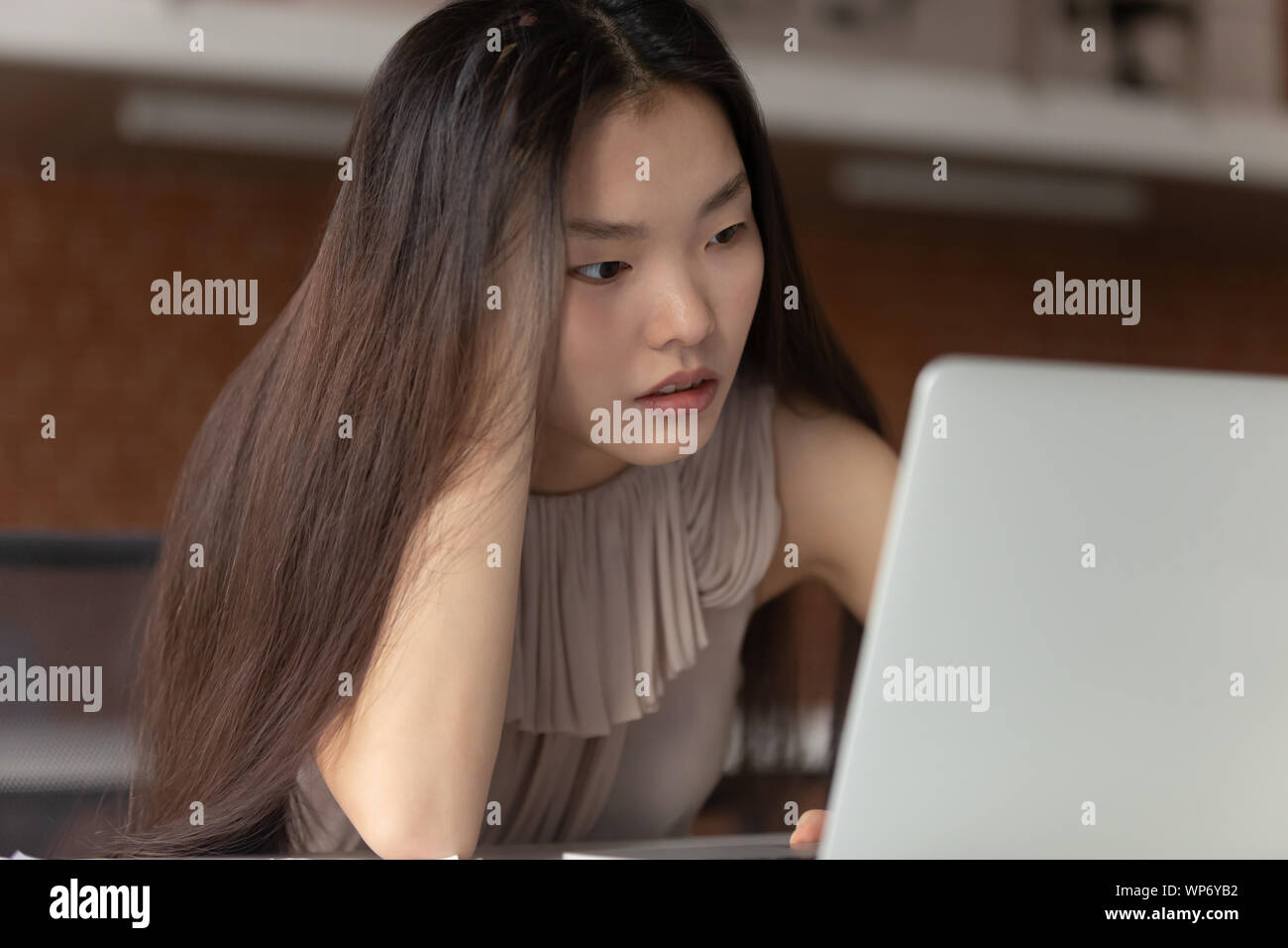 Stressed young asian female employee stuck with difficult task. Stock Photo