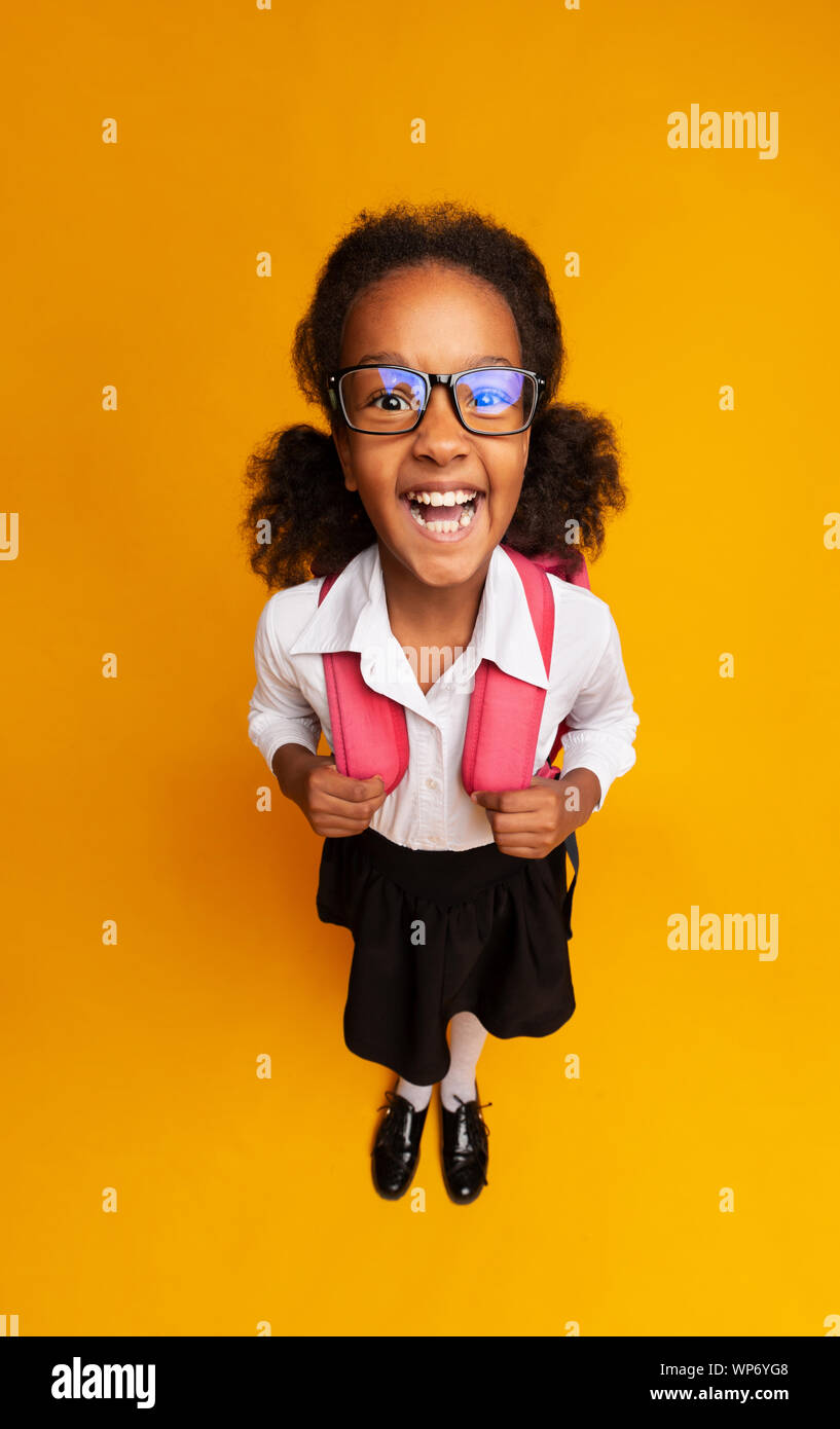 African American Schoolgirl Laughing At Camera Over Yellow Background Stock Photo
