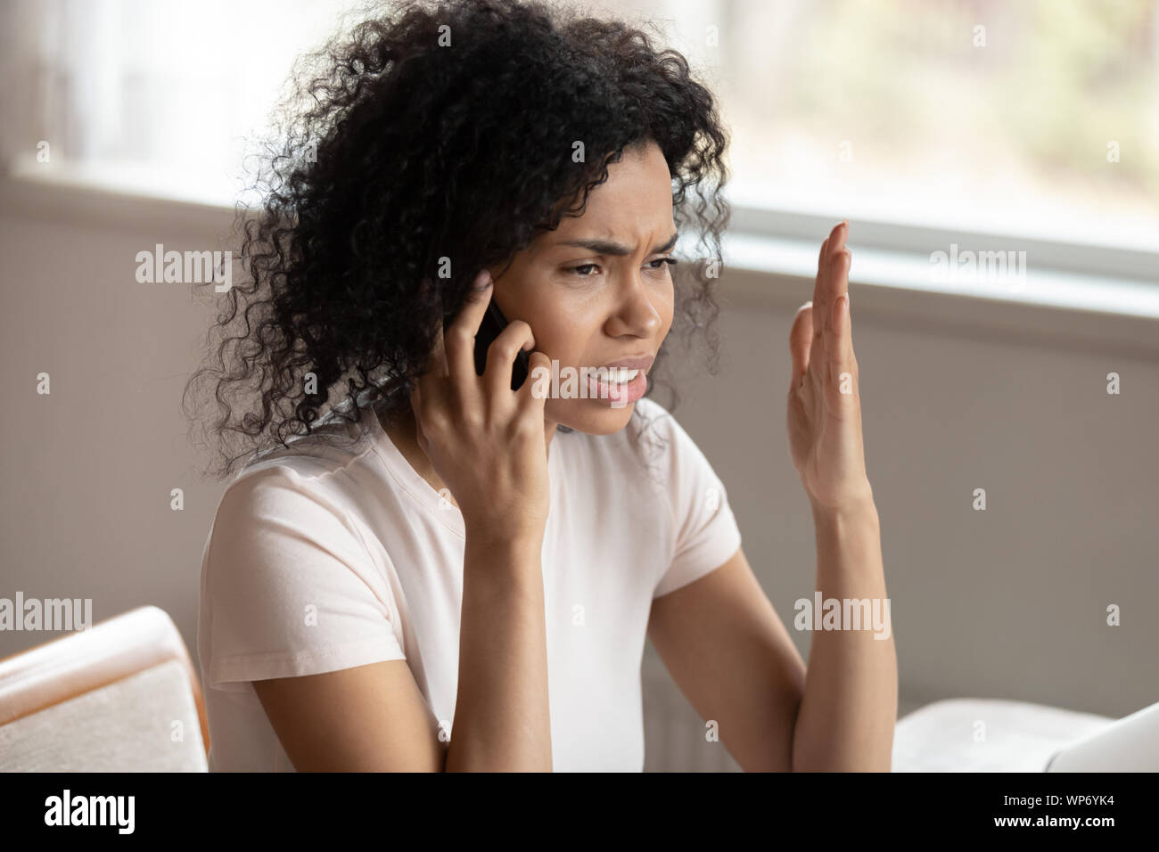 Unhappy biracial woman having unpleasant cellular call Stock Photo