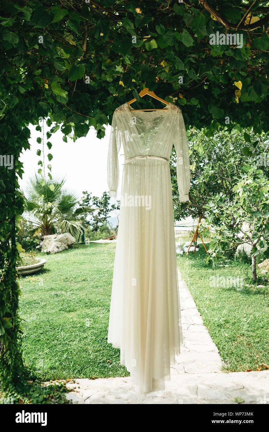 Wedding dress hanging on a hanger outdoor. Preparing for the wedding. Stock Photo