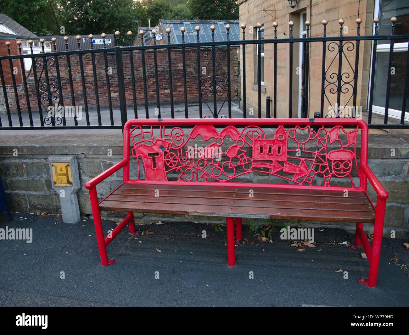 Red metal bench with sculpture pictures celebrating the tour de france bike race in 2014 which passed along the road by the bench Stock Photo