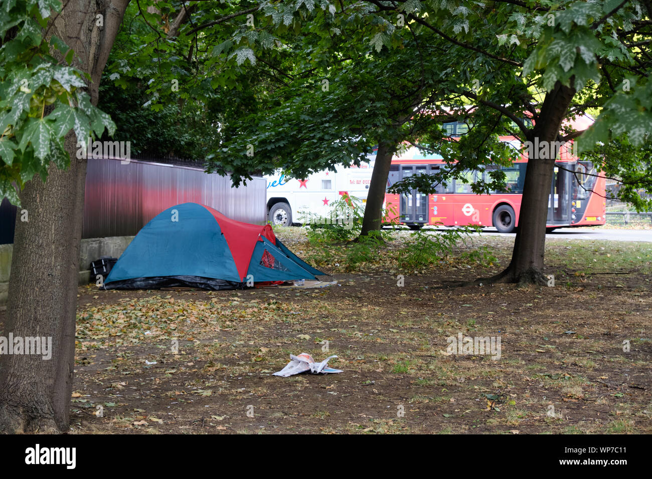 Tent set up by homeless person in public space in London by Hyde Park, with Red bus in background Stock Photo