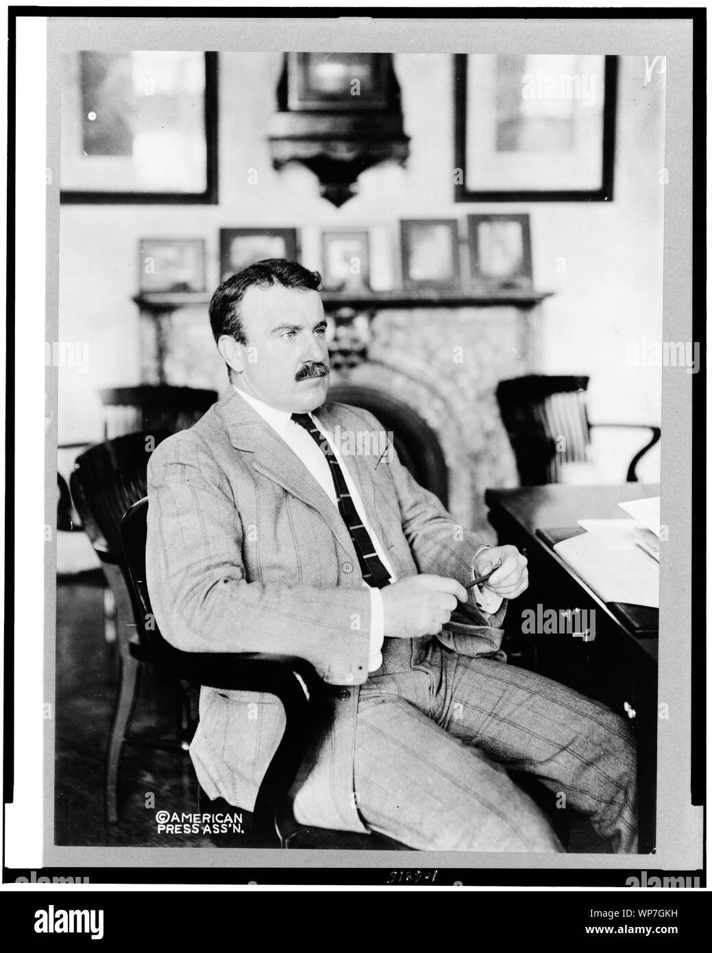Lee McClung, threequarter length portrait, seated at desk, facing