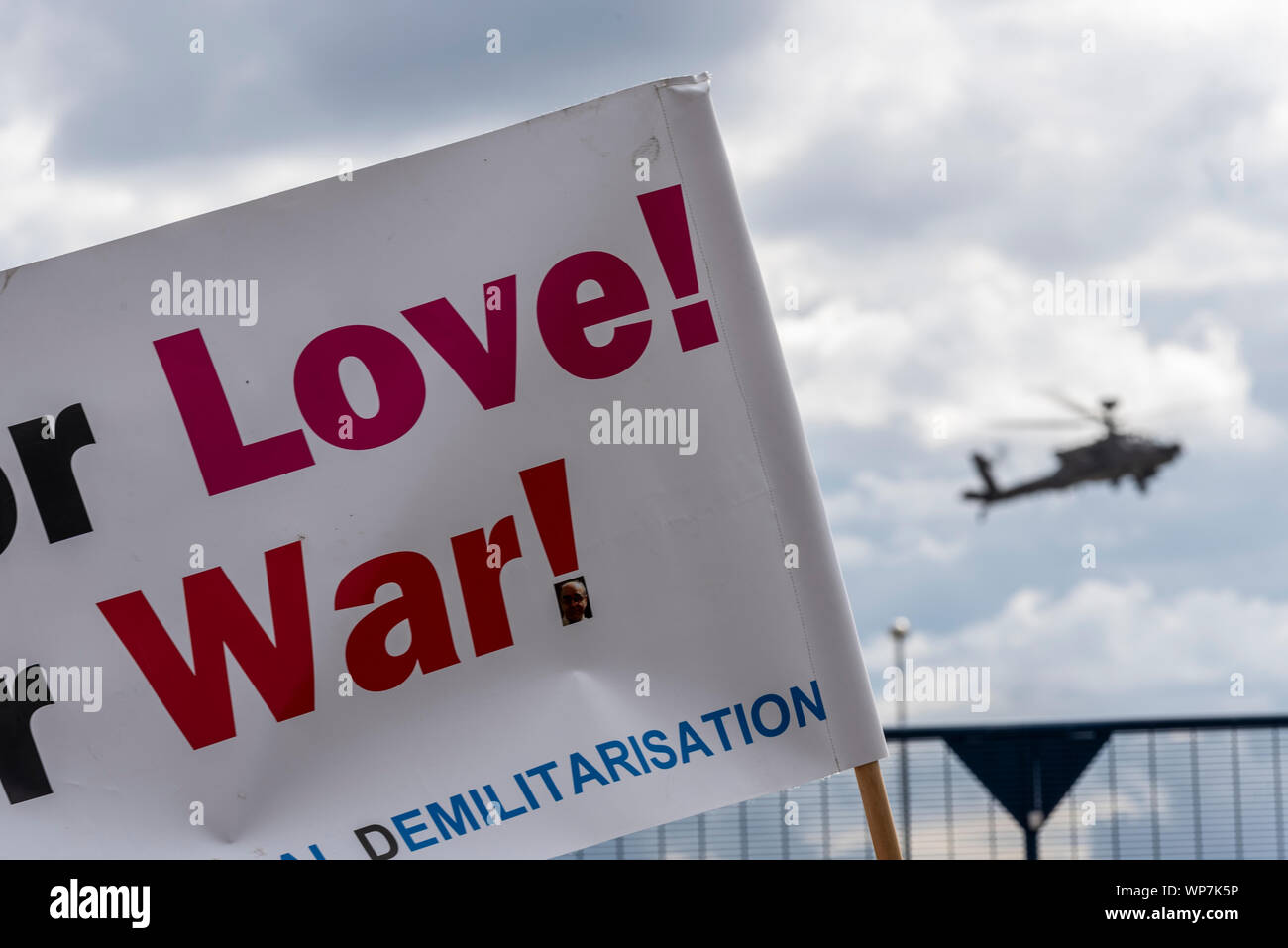 US Army AH-64 Apache gunship landing at Defence & Security Equipment International DSEI arms fair trade show, ExCel, London, UK. Protest banner Stock Photo