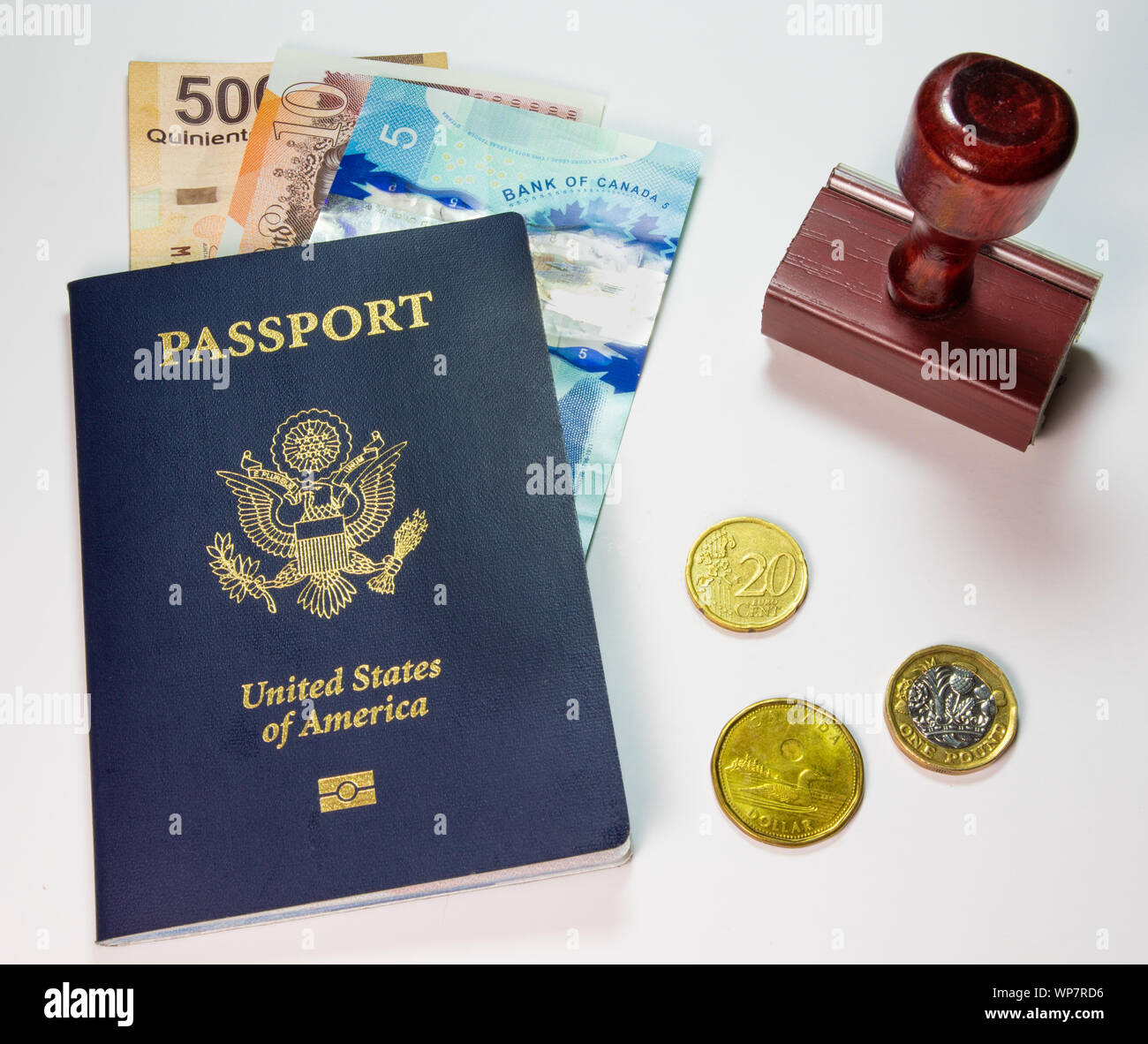 Travel Concept with blue U.S. American Passport, Stamp and Foreign Currency displayed on a plain background Stock Photo