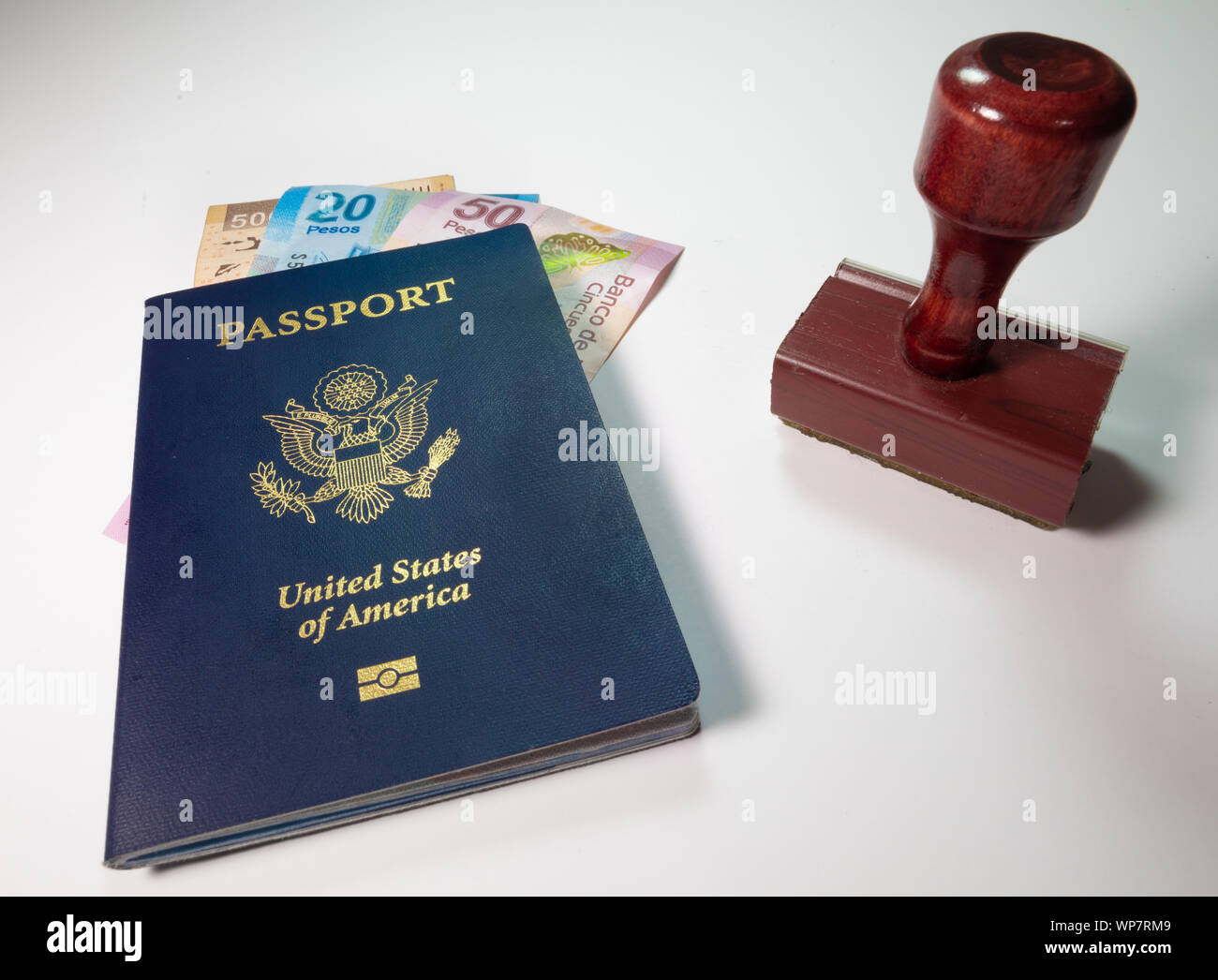 Mexico Travel Requirements Concept with blue U.S. American Passport, Stamp and Mexican Pesos displayed on a plain background Stock Photo