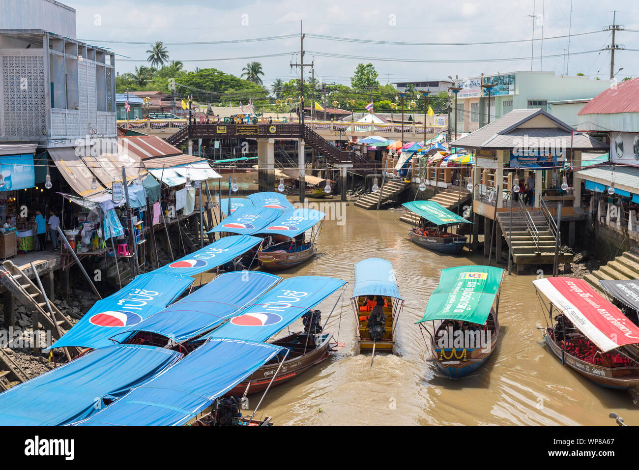 Amphawa, Thailand - June 15, 2019: a fleet of traditional Thai boats with Pepsi logos at Amphawa Floating Market. Stock Photo