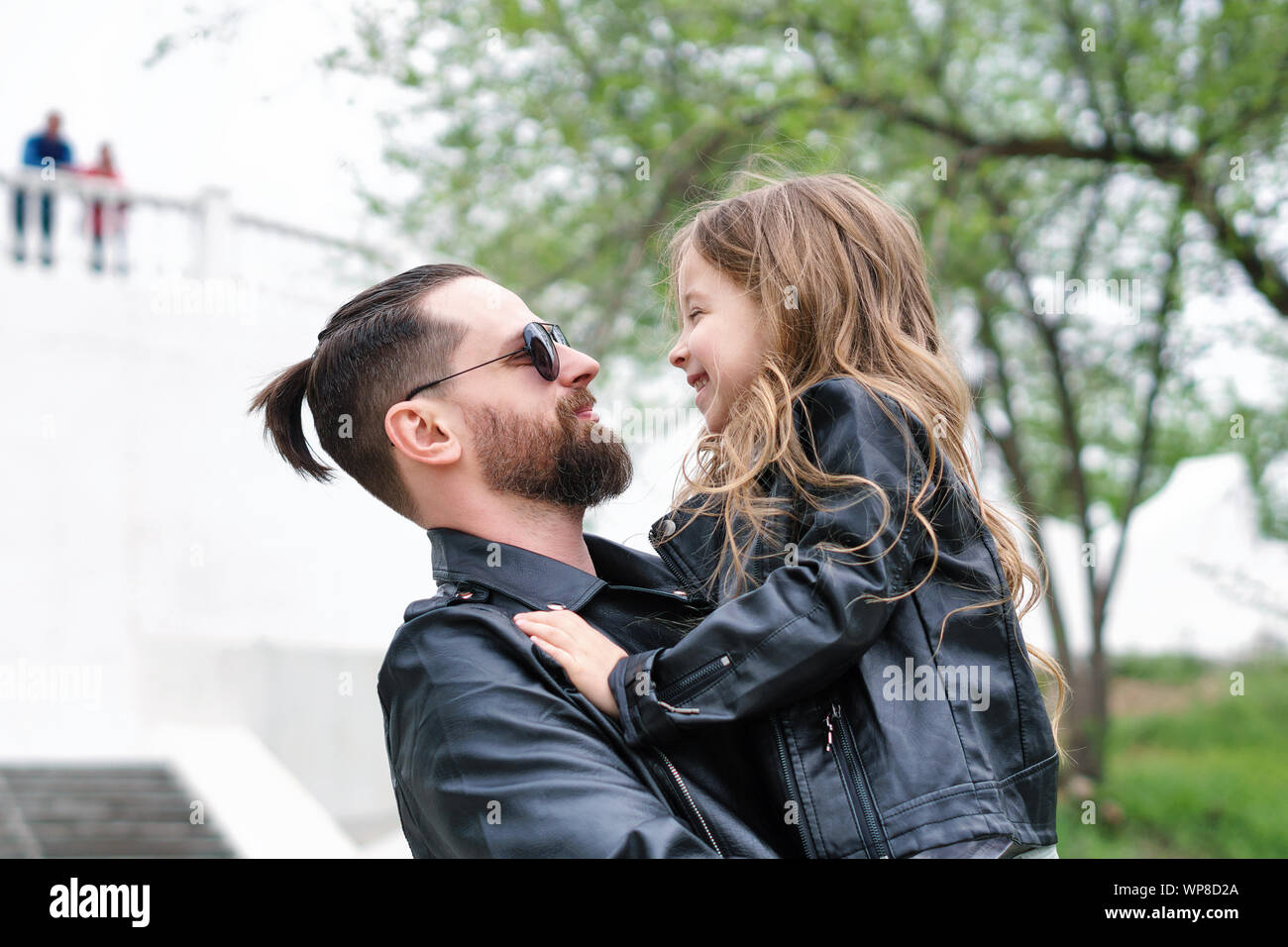 Fashionable stylish family for a walk. Daughter in the hands of dad. Happiness being a parent. Unconditional love. Time together. Family look. Urban c Stock Photo