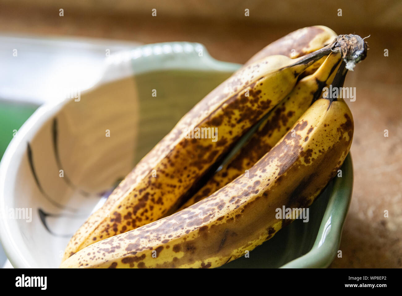 Close up of ripe bananas in decorative bowl on kitchen counter Stock Photo