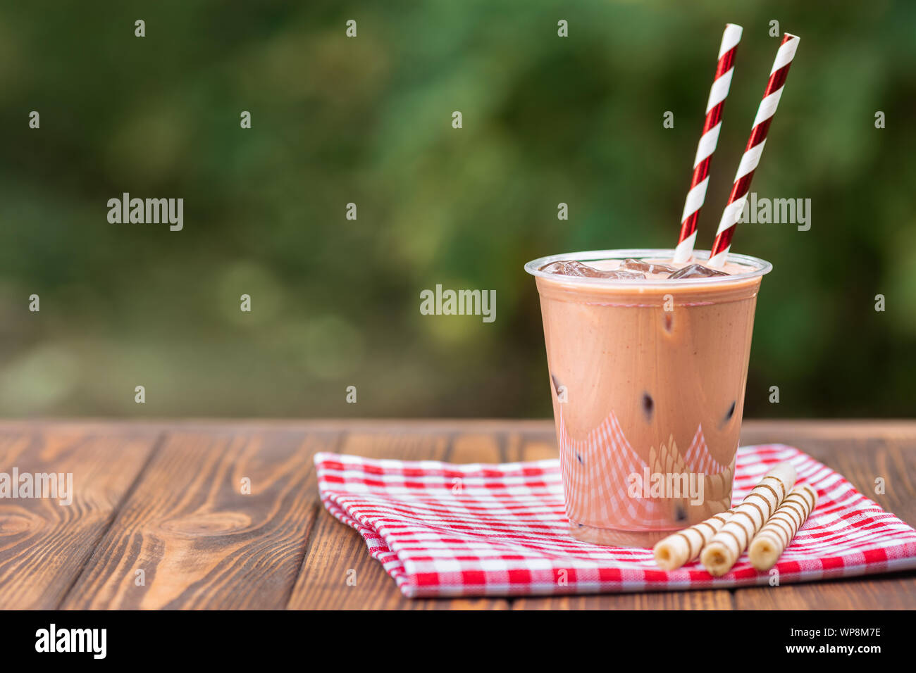 https://c8.alamy.com/comp/WP8M7E/ice-chocolate-milkshake-in-disposable-plastic-cup-with-wafer-rolls-on-wooden-table-outdoors-WP8M7E.jpg