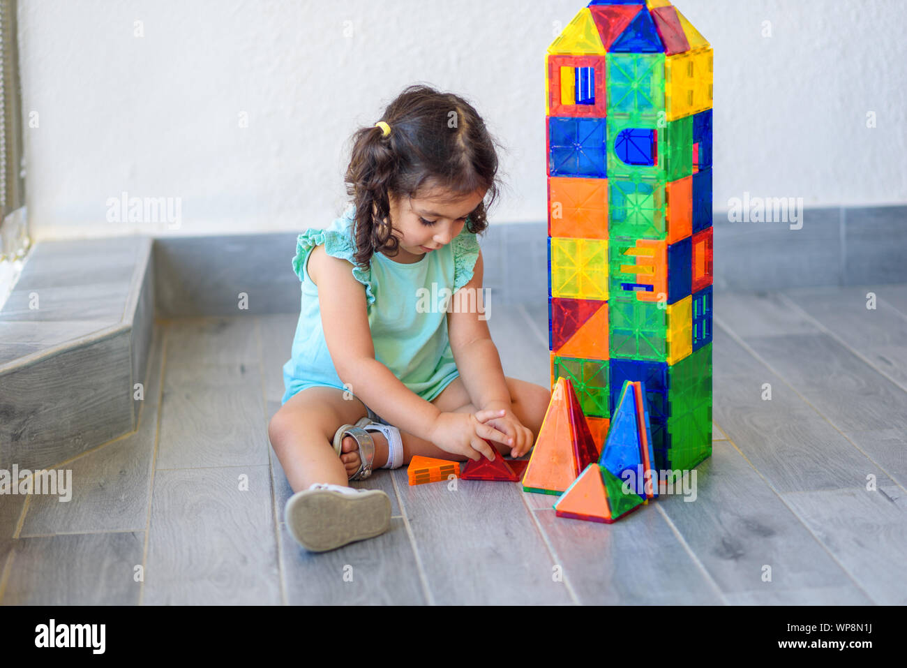 Little girl playing with lots of colorful plastic blocks constructor ...