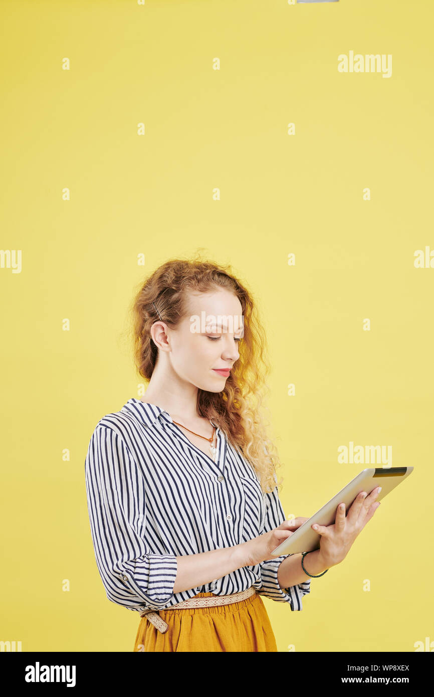 Serious young female entrepreneur using application on tablet computer for communication with coworkers and business partners Stock Photo