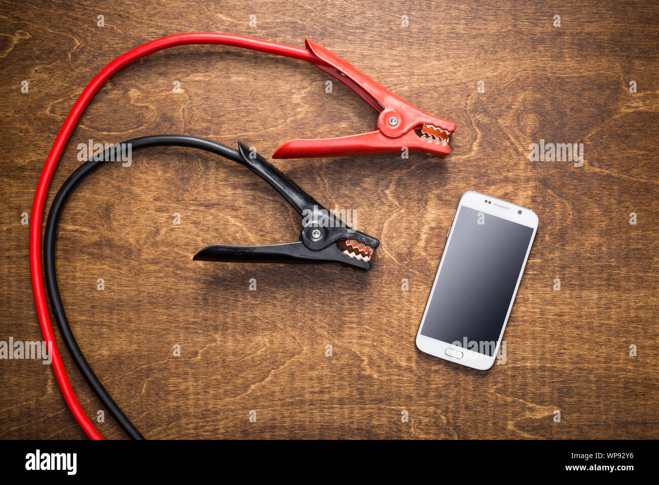 Charching clamps near smartphone with dead battery. Phone charging, energy efficiency concept. Stock Photo