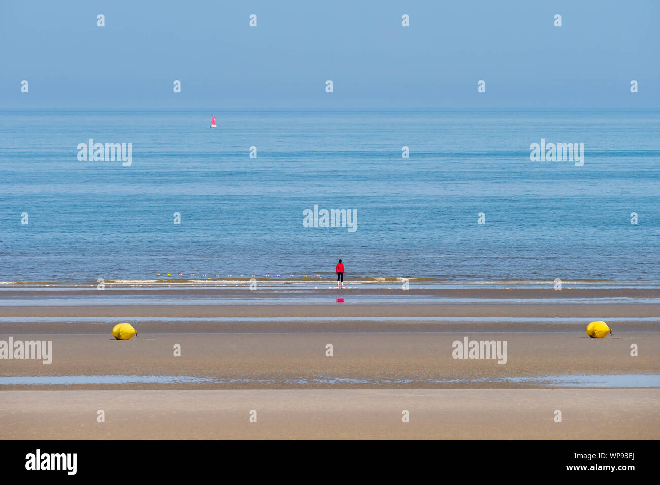 One woman in the distance enjoying an empty beach and the view across the ocean at Bray-Dunes in France Stock Photo