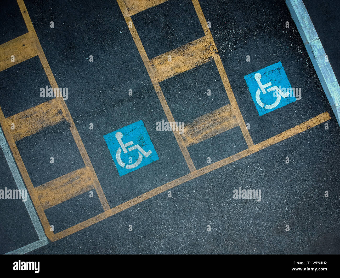 Disabled blue parking sign painted on dark asphalt. Empty handicapped ...