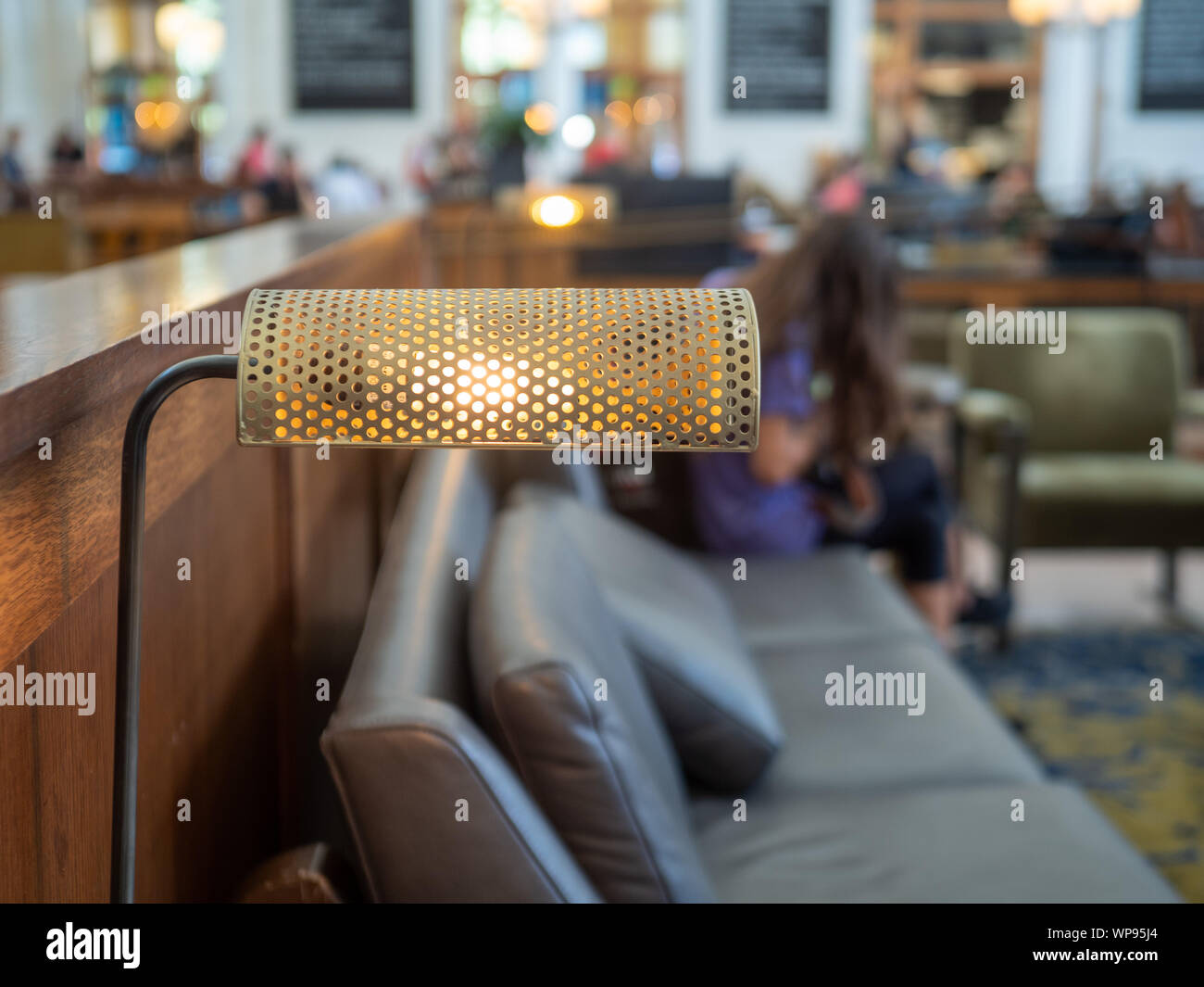 Desk lamp at table of train station with woman traveler waiting on chair Stock Photo