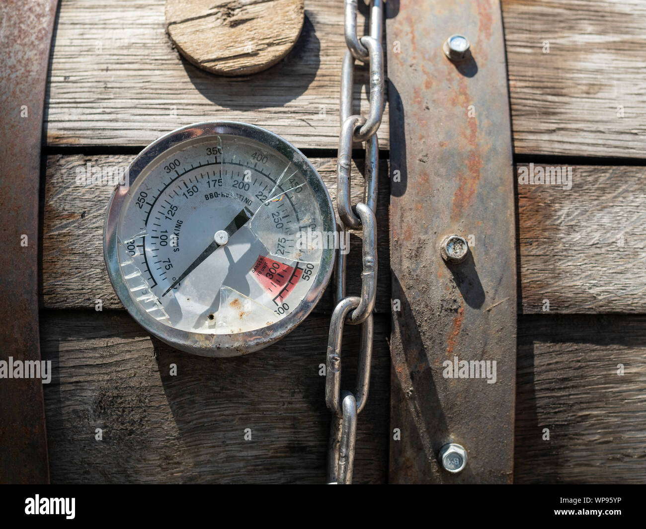 Broken thermometer gauge and chain sitting on top of smoker grill bbq Stock Photo
