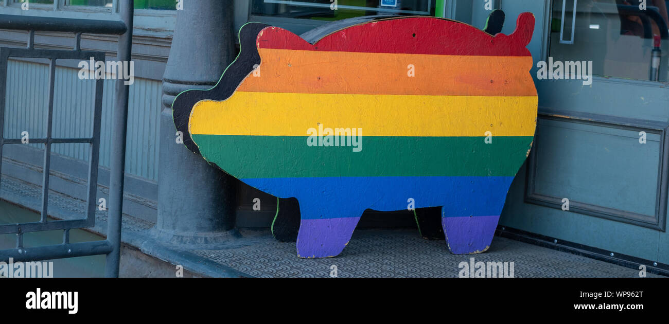 Rainbow colored pig stand sign sitting outside of store Stock Photo