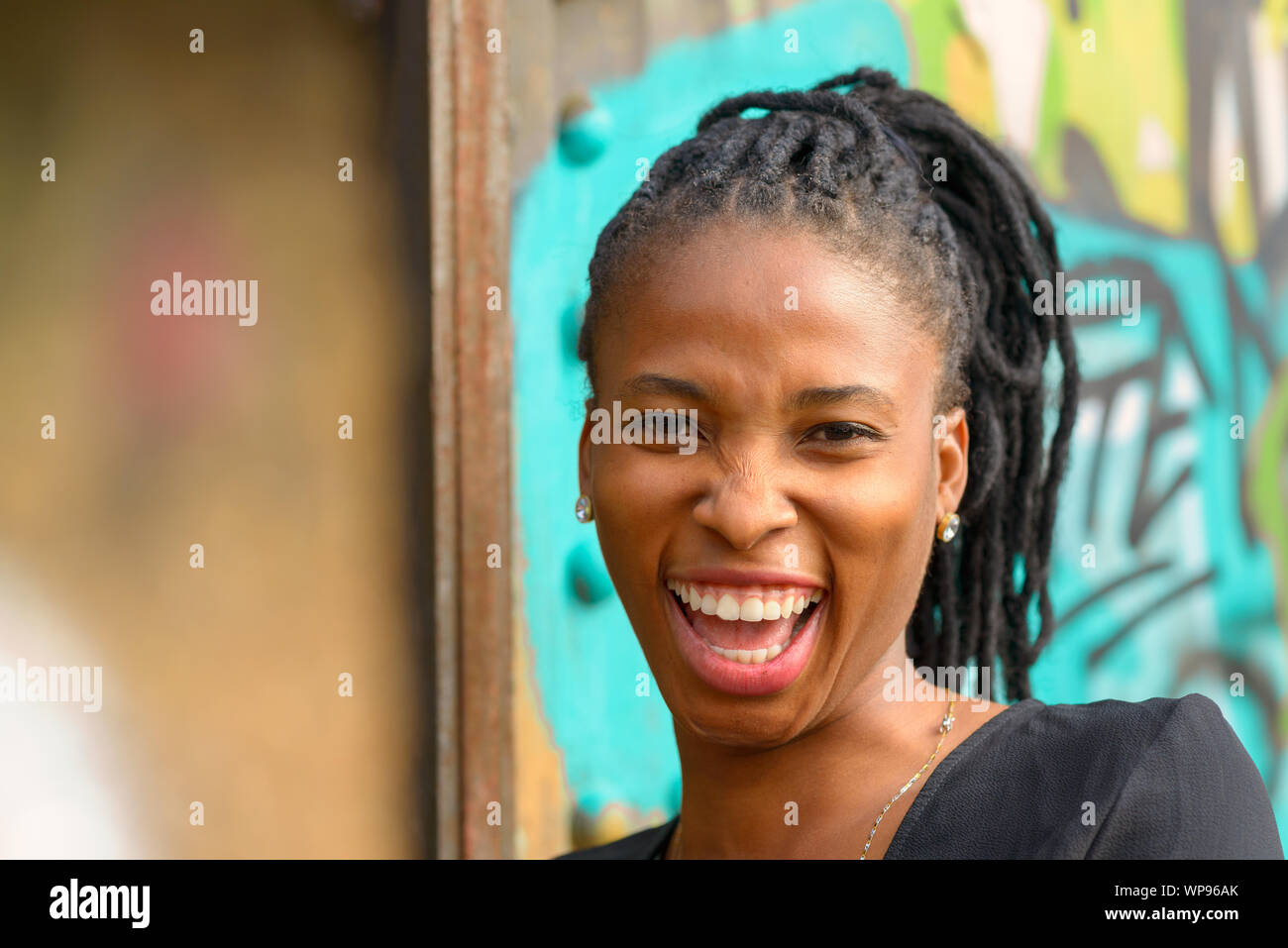 Attractive young African woman with a vivacious smile laughing at the ...