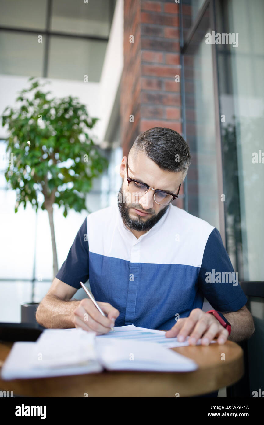 Bearded businessman making some notes while studying Stock Photo
