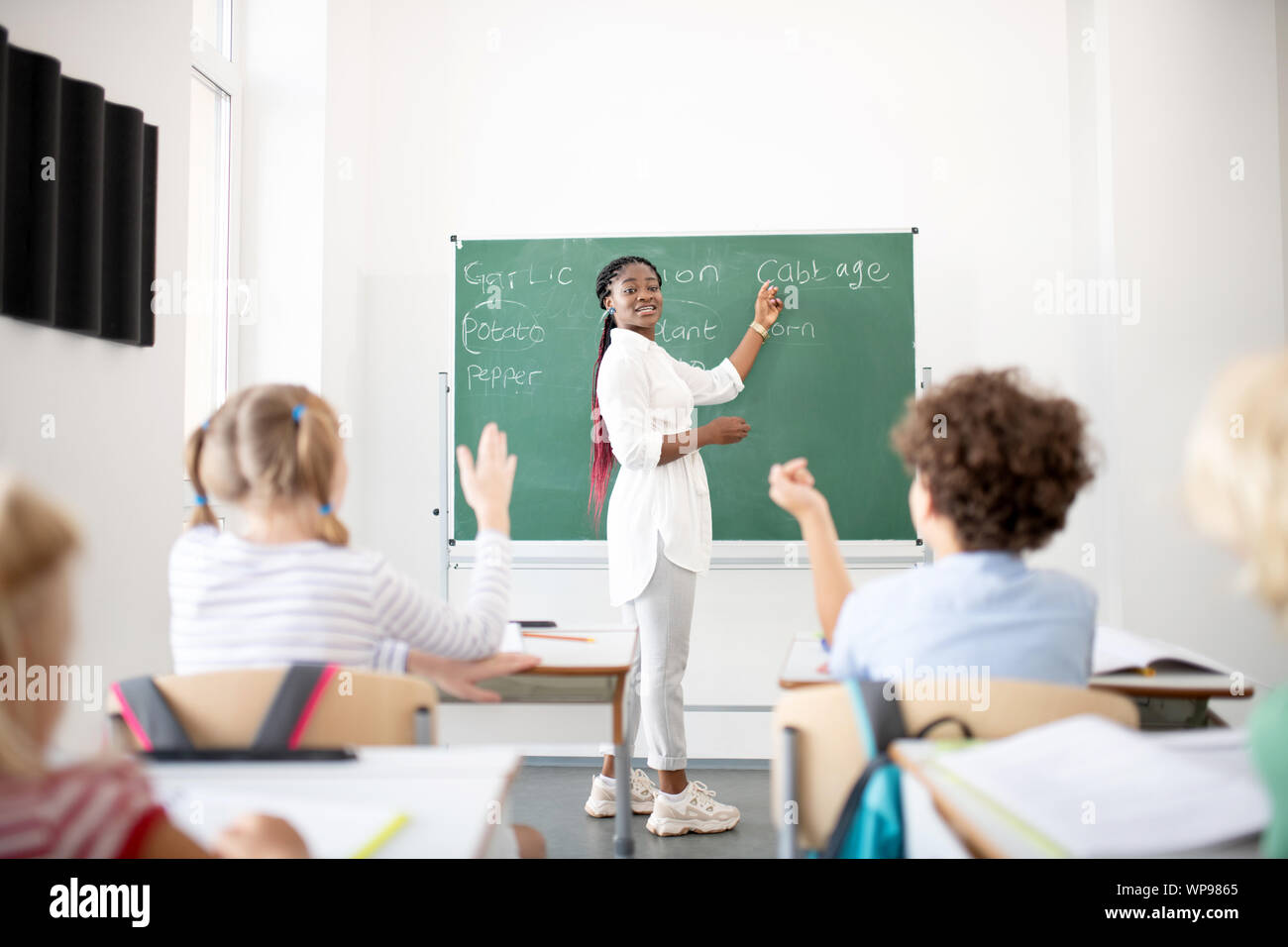 Active children raising hands while knowing the answer Stock Photo - Alamy