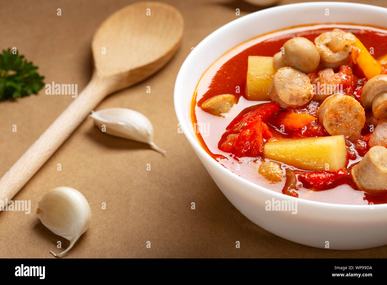 Stew or soup made from vegetables and german sausages in a white bowl Stock Photo
