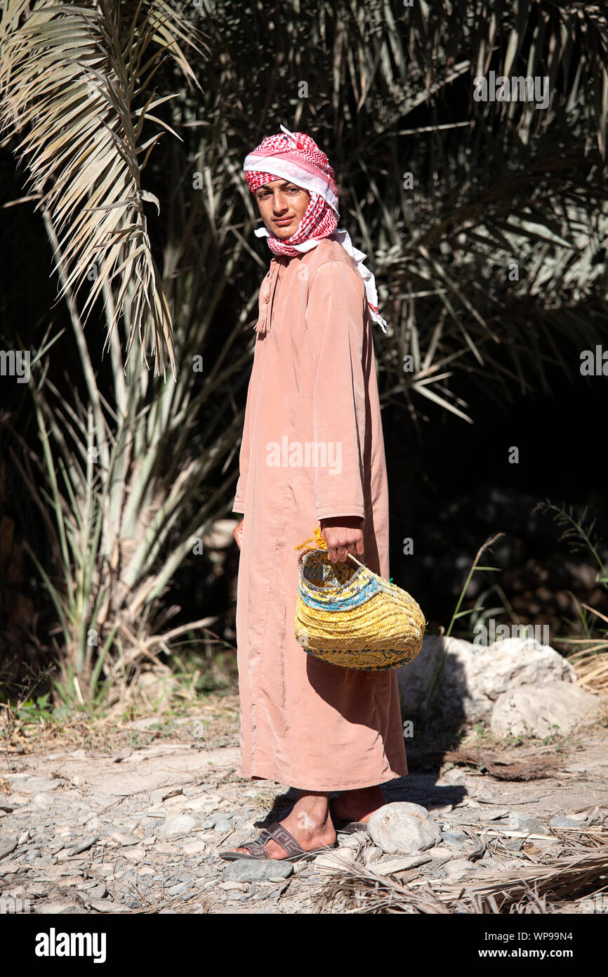 Young man in traditional clothes wearing head scarf and holding a basket, Oman Stock Photo