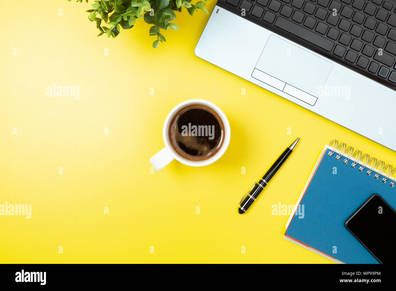Laptop, notebook, smartphone, coffee and pen on yellow background. Office desk table with modern accessories Stock Photo