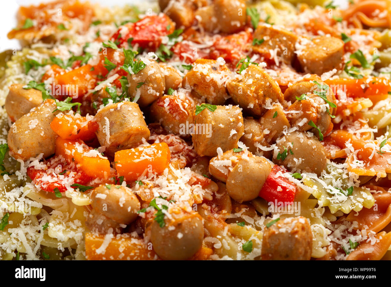 Farfalle pasta with sausages, vegetables and grated parmesan on plate - close up view Stock Photo