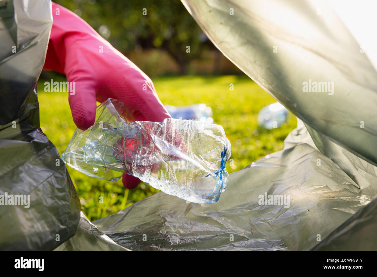 Young volunteer with garbage bag picking up trash outdoor, cleaning