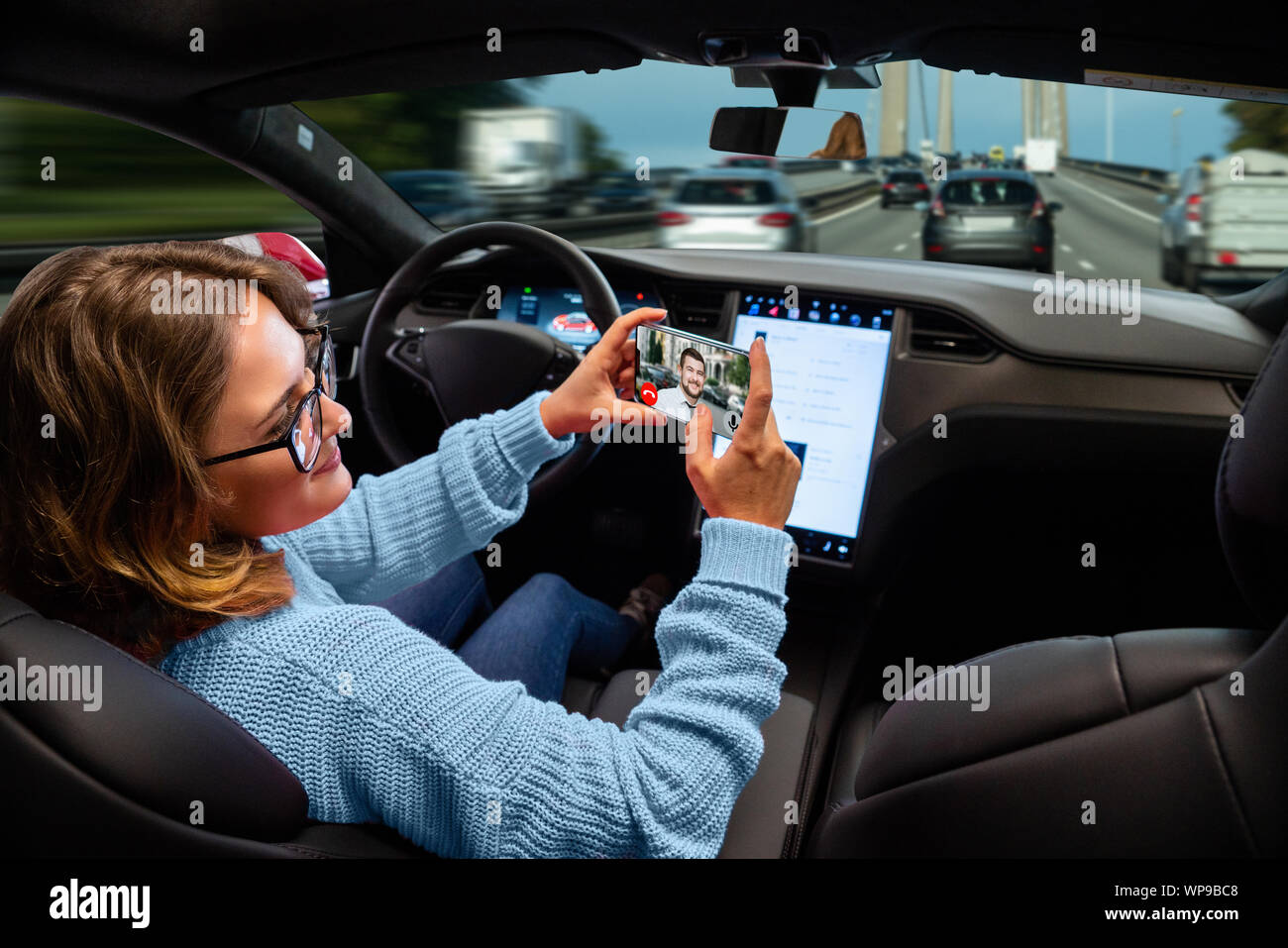 Woman communicates by video call while her car is driven by an autopilot. Self driving and autonomous vehicle concept Stock Photo