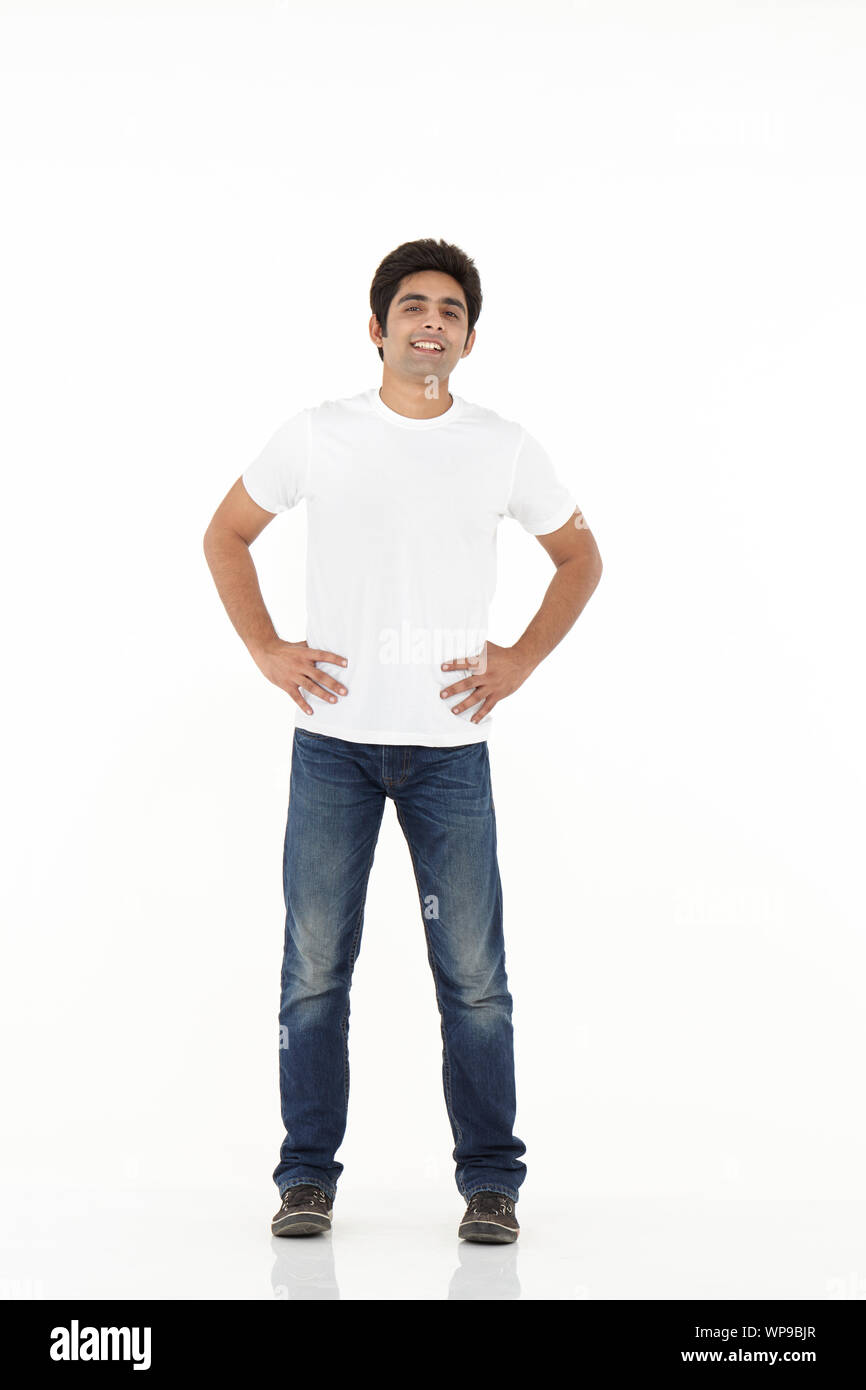 Young man smiling with his arms akimbo Stock Photo