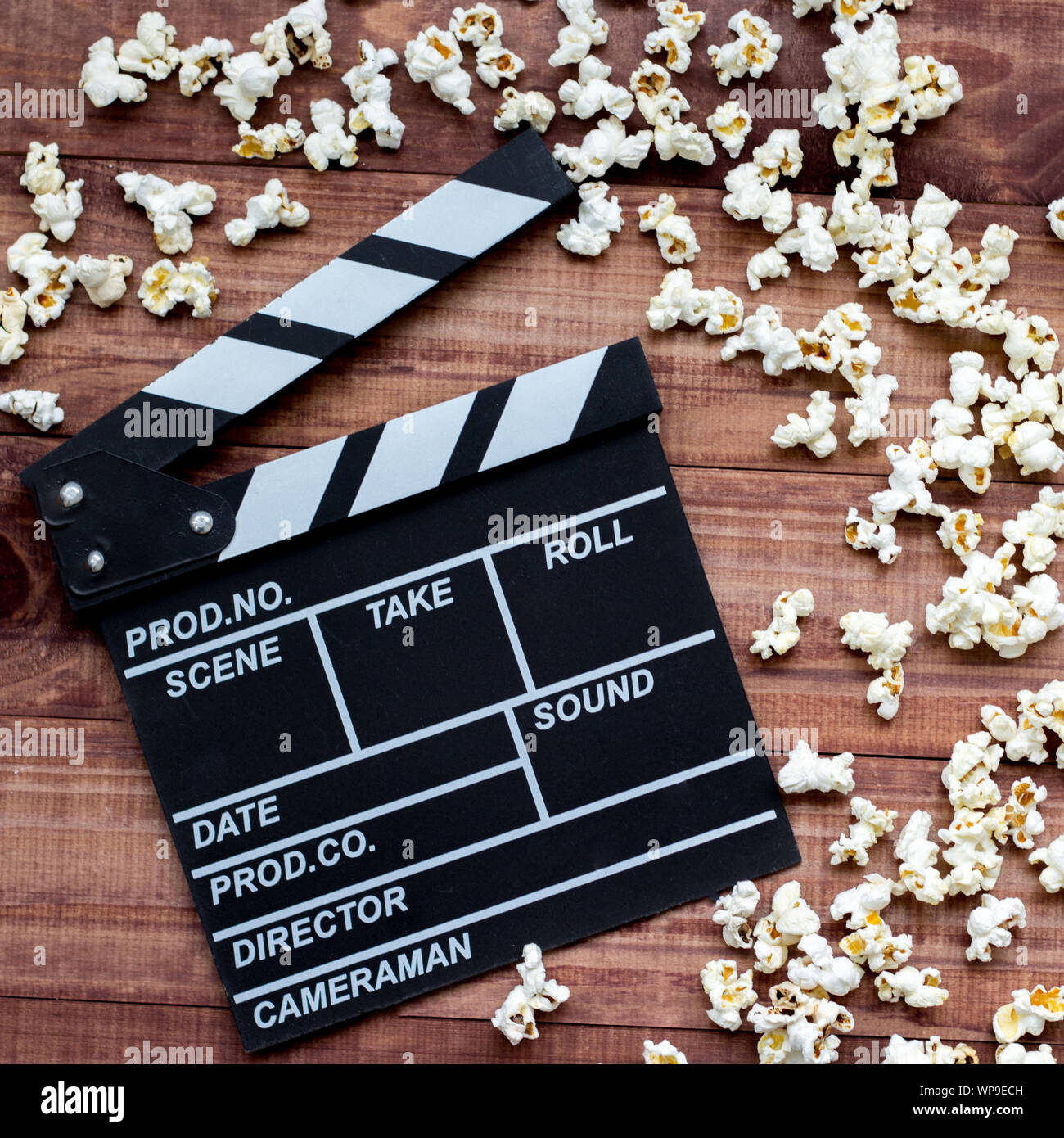 Watching the film. Movie clapperboard and popcorn on blue wooden table ...