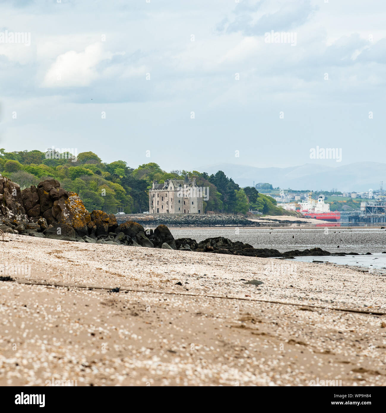 Scottish coastline covered by seashells and an old castle Stock Photo
