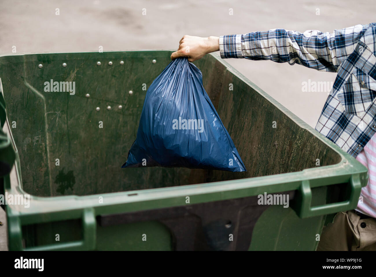male dumping waste package into a big trash bin containers Stock Photo