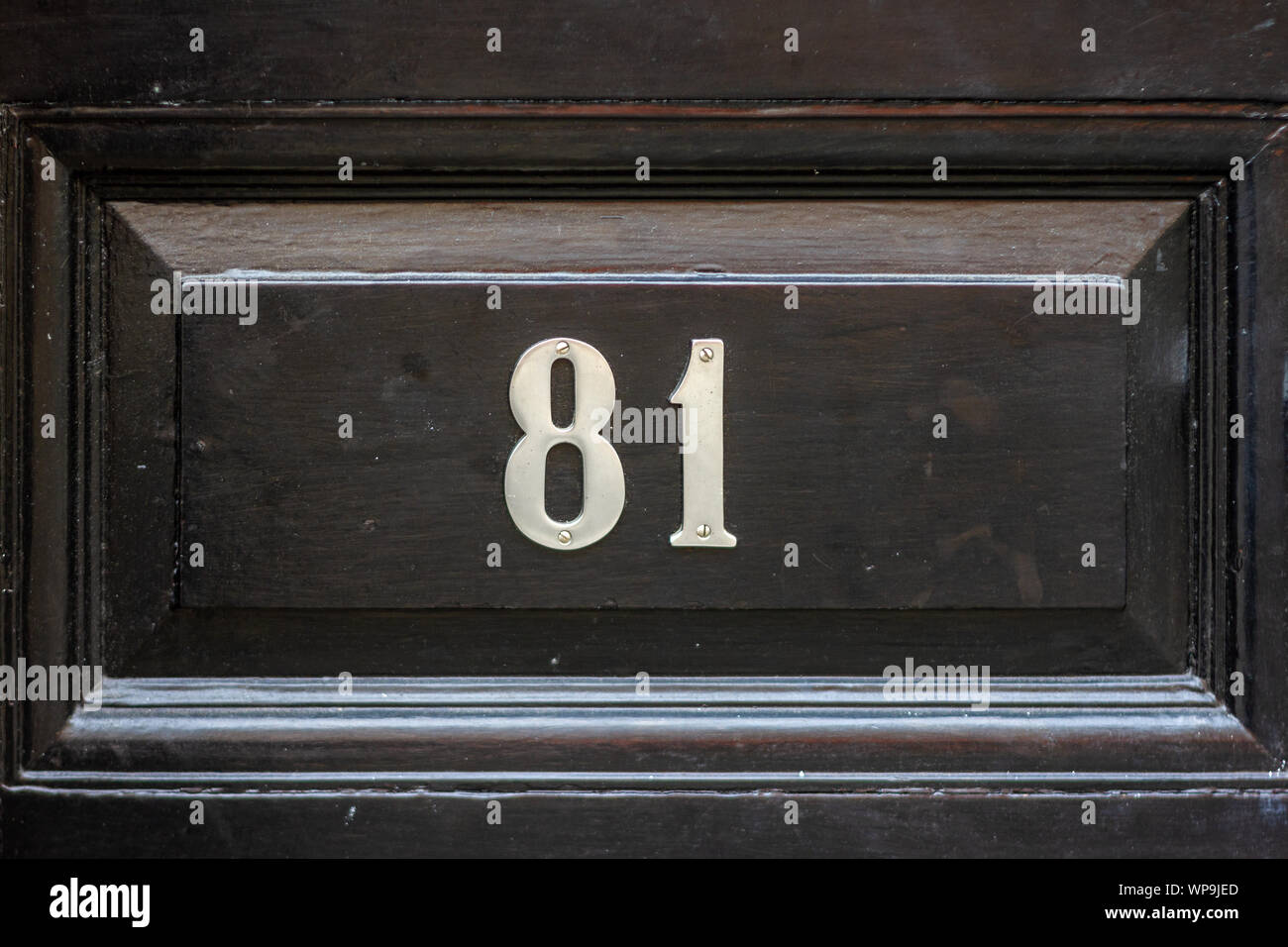 House number 81 on a black wooden front door Stock Photo